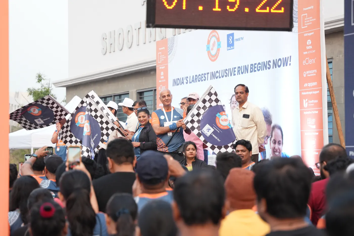 The flag-off crowd at Edition 2, waving chequered flags under the start banner