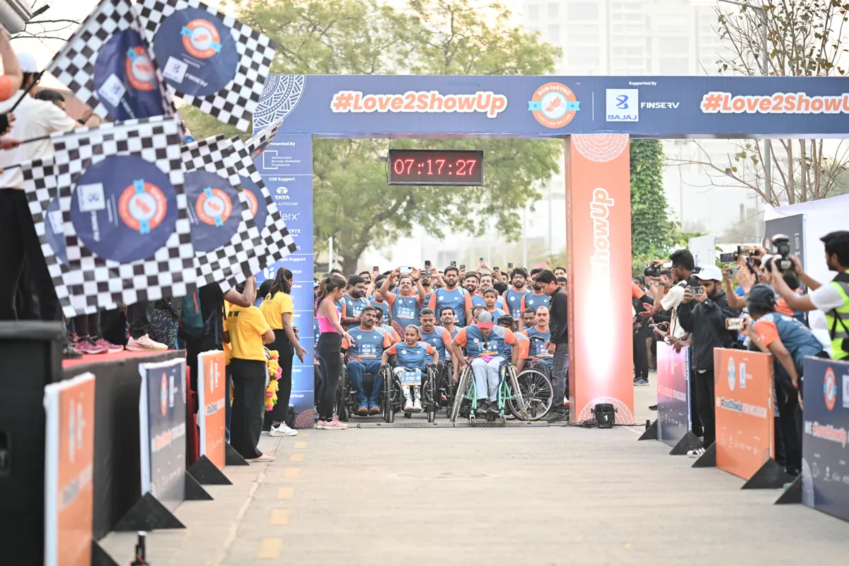A wave of wheelchair users and runners starting together under the finish arch